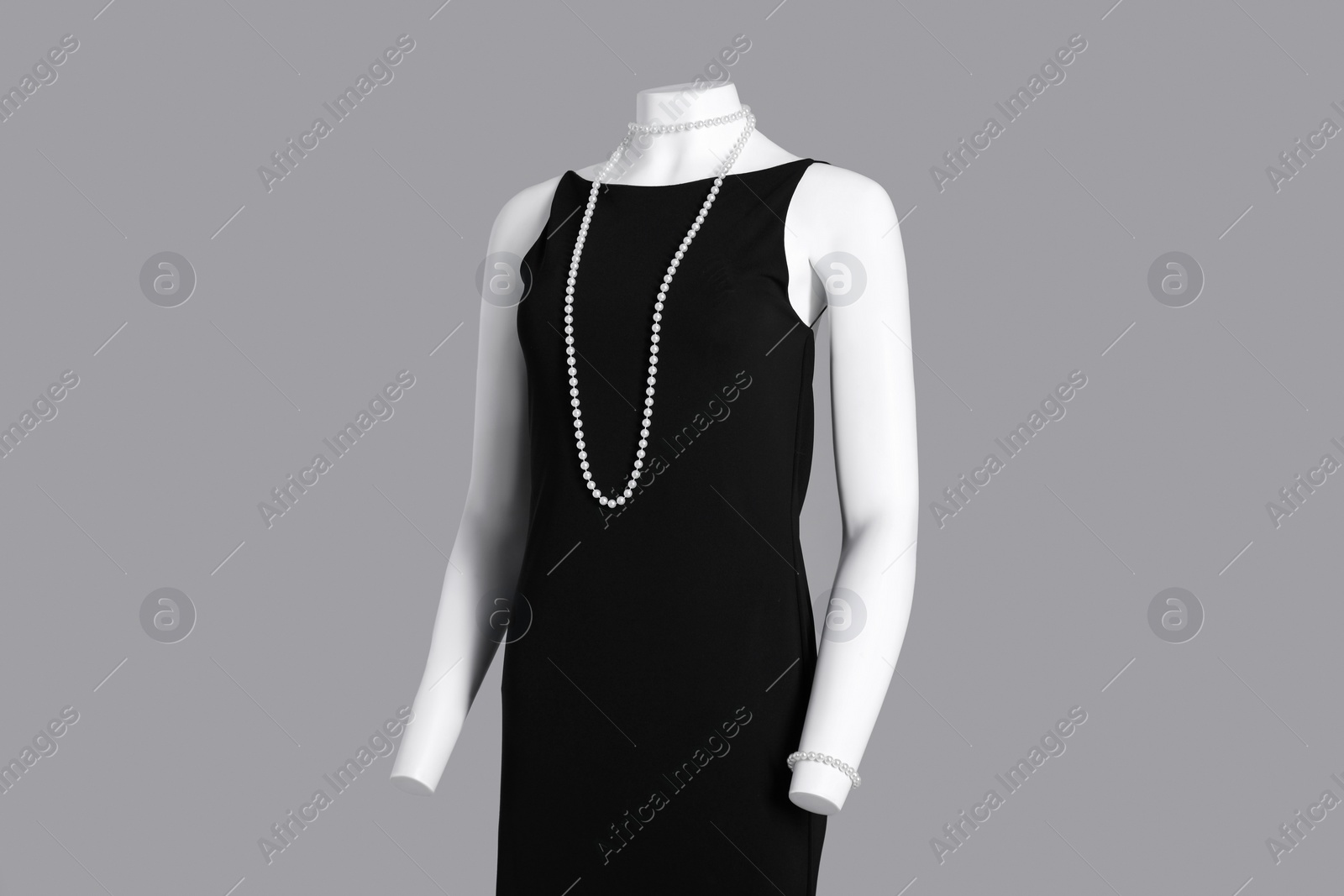 Photo of Female mannequin with necklace dressed in elegant black dress on grey background