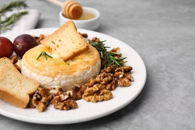 Photo of Tasty baked camembert and different products on gray table, closeup