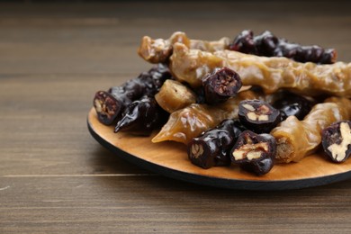 Photo of Many delicious sweet churchkhelas on wooden table, closeup