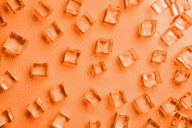 Cold ice cubes and water drops on background, flat lay. Toned in orange