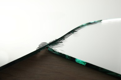 Shard of broken mirror on wooden backing board, closeup