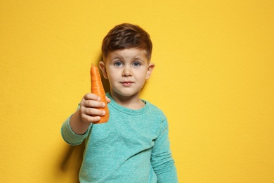 Adorable little boy with carrot on color background. Space for text