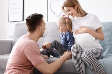 Photo of Young pregnant woman with her family at home