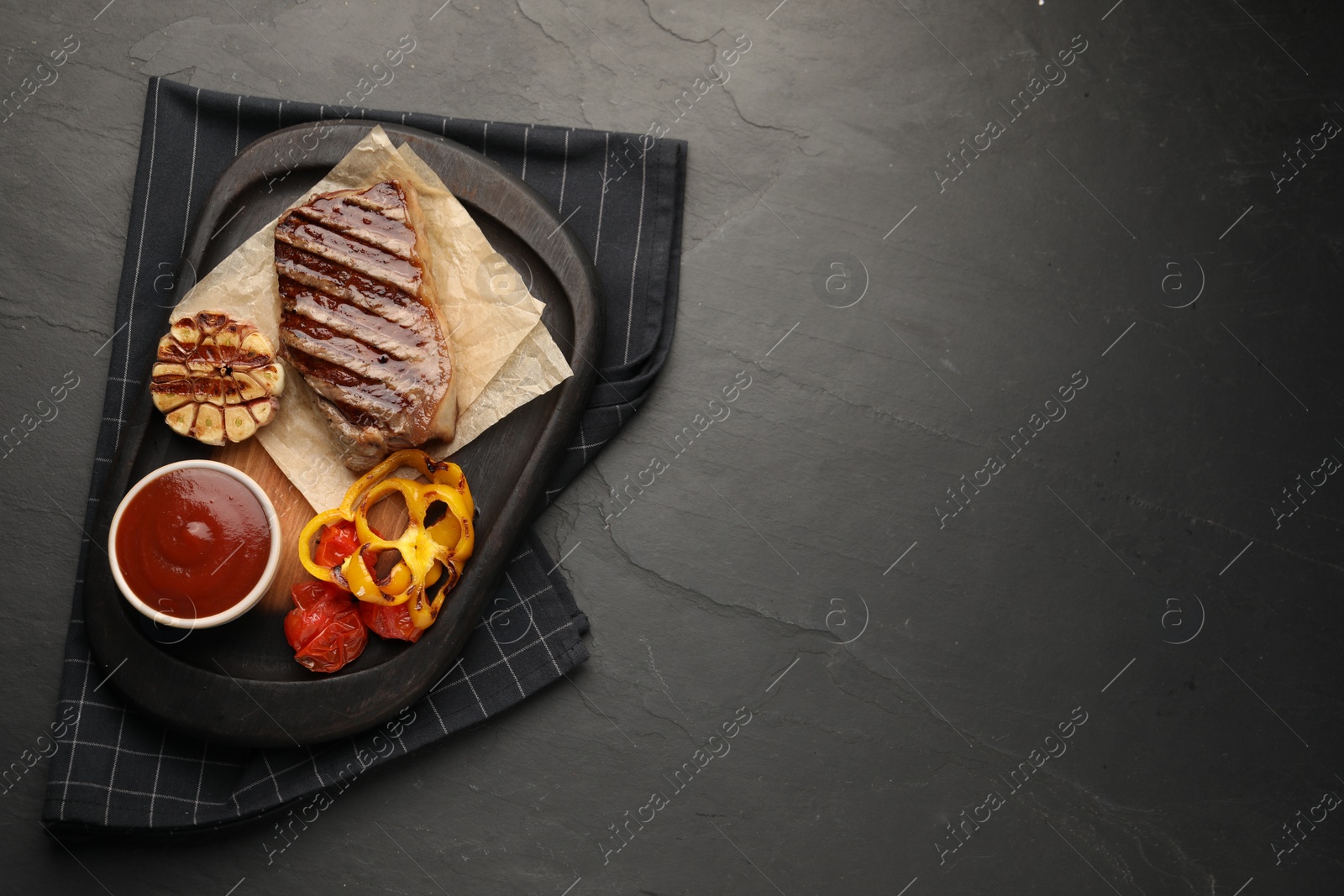 Photo of Delicious grilled beef steak with spices and tomato sauce on dark gray table, top view. Space for text