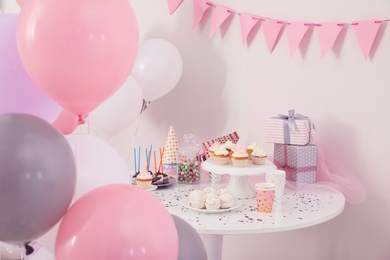 Photo of Party treats and items on table in room decorated with balloons