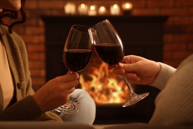 Photo of Lovely couple with glasseswine spending time together near fireplace at home, closeup