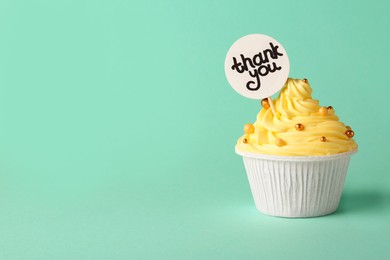 Photo of Tasty cupcake and note with phrase Thank You on turquoise background, space for text