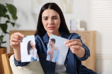 Photo of Upset woman holding parts of torn photo at home. Divorce concept