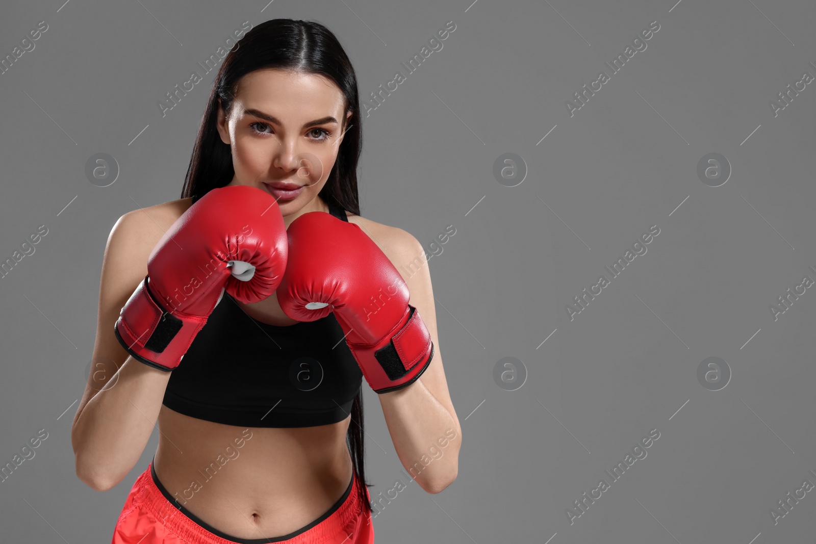 Photo of Beautiful woman in boxing gloves on grey background. Space for text