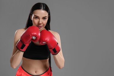 Photo of Beautiful woman in boxing gloves on grey background. Space for text