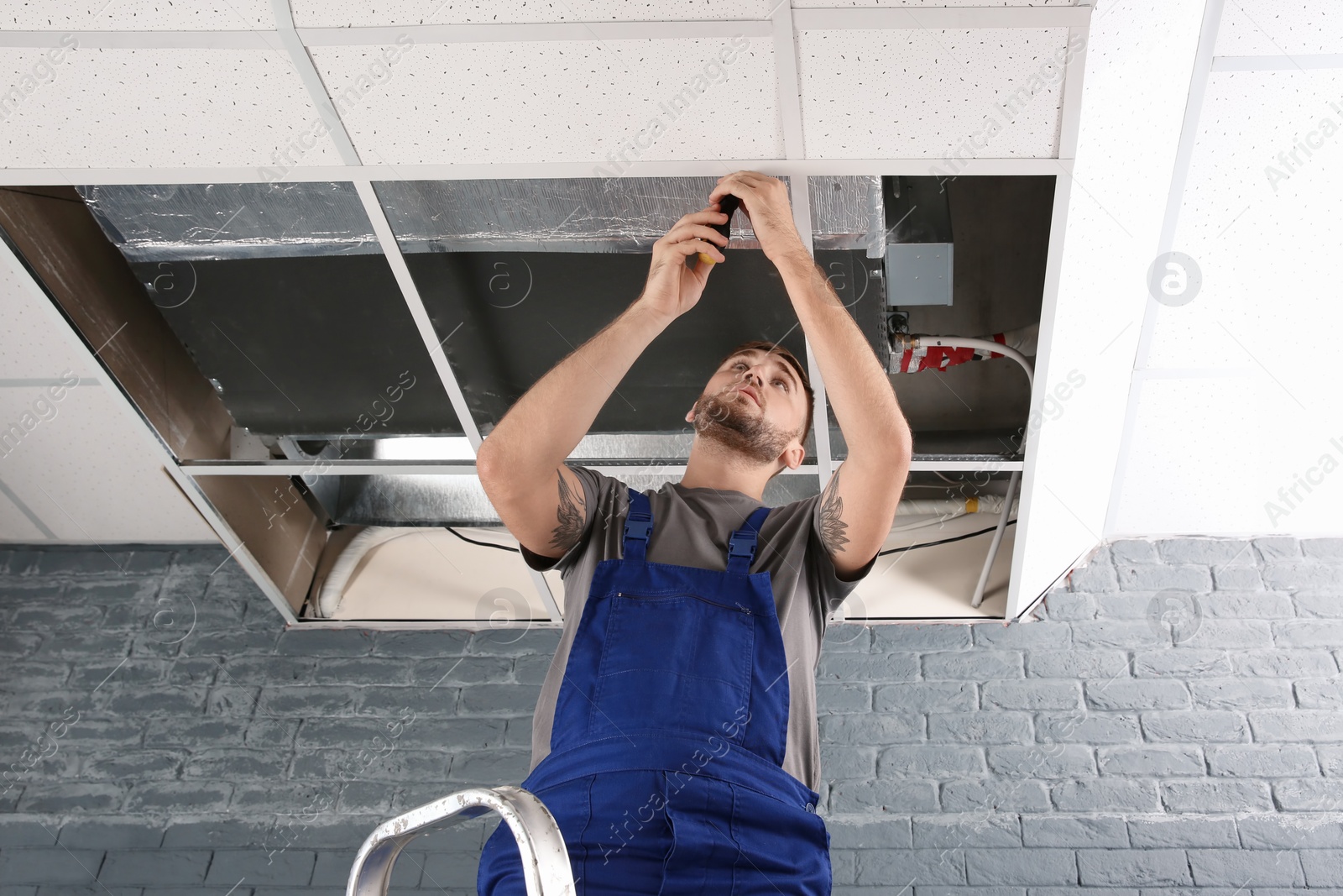 Photo of Young male technician repairing air conditioner indoors