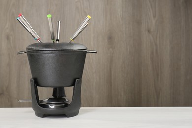 Fondue set on white wooden table, space for text