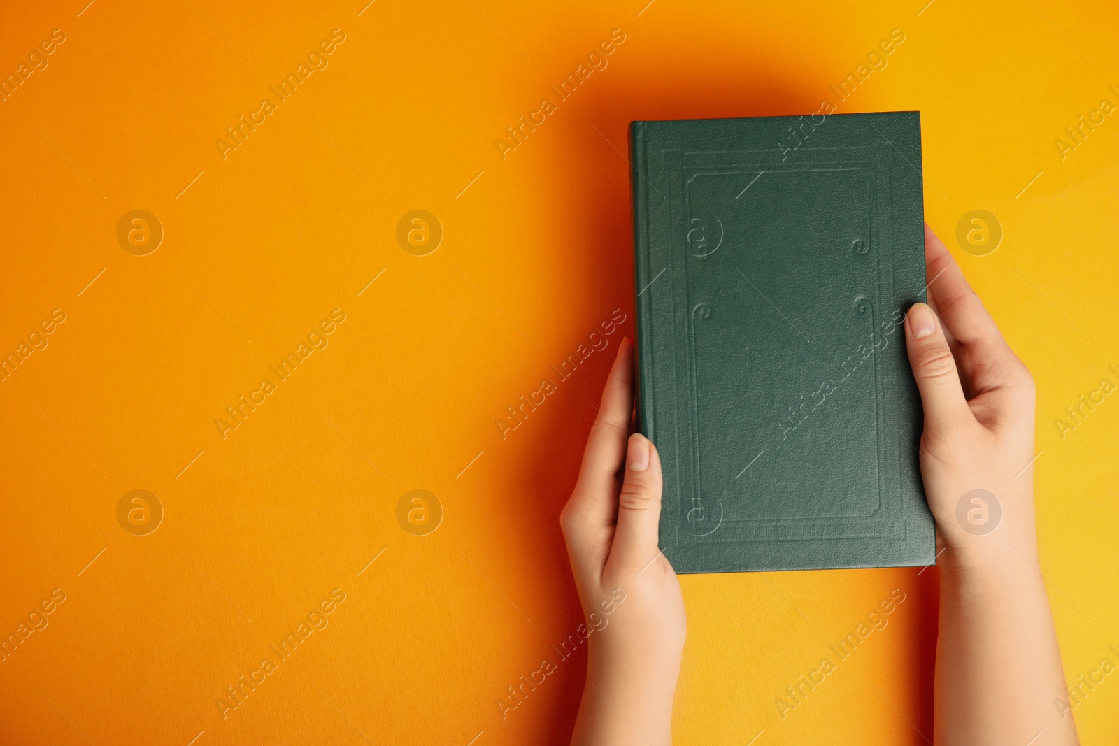 Photo of Woman with book on orange background, top view. Space for design