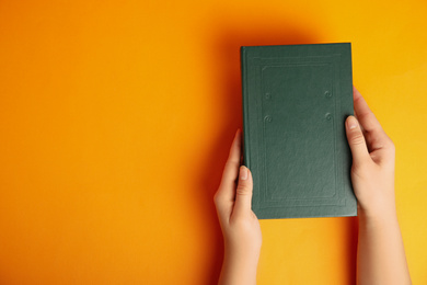 Photo of Woman with book on orange background, top view. Space for design
