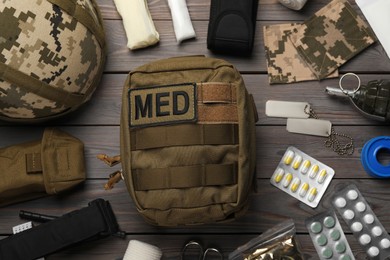 Photo of Military first aid kit on wooden table, flat lay