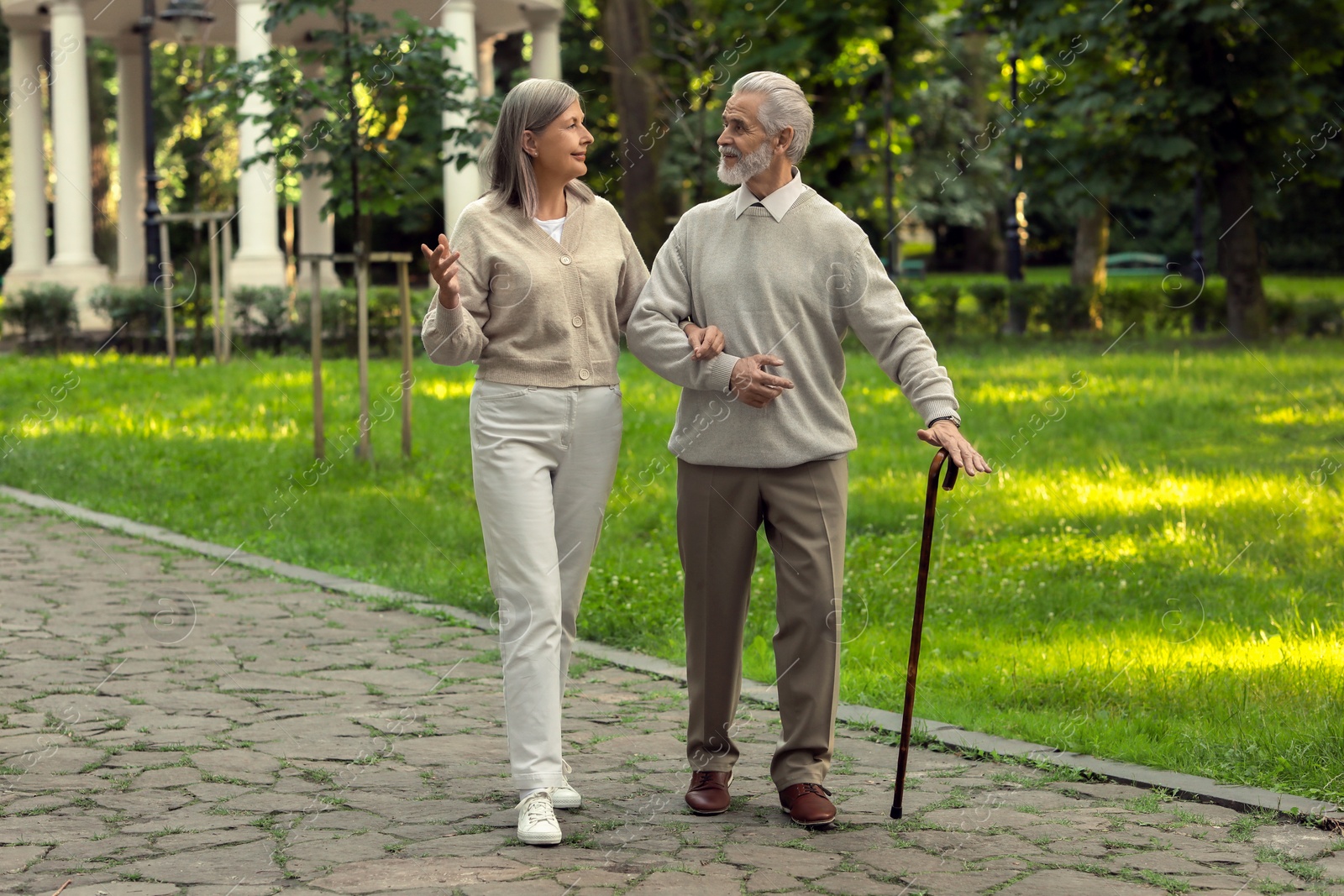 Photo of Senior man with walking cane and mature woman in park