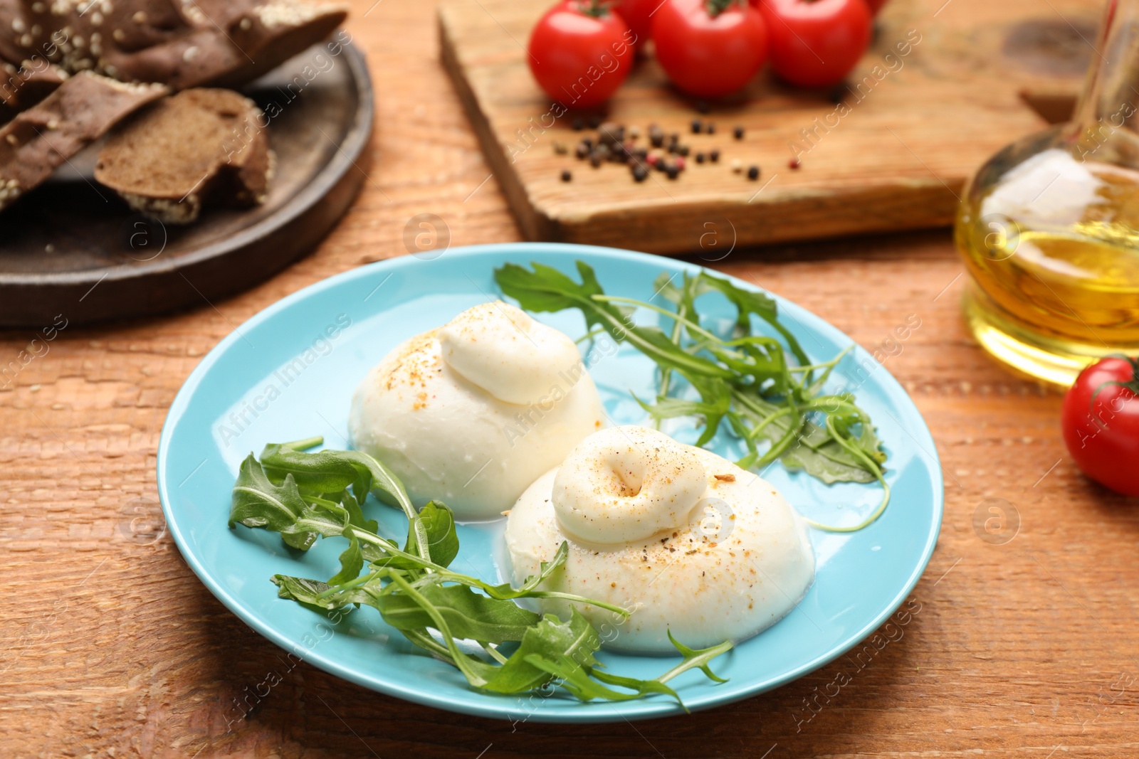 Photo of Delicious burrata cheese with arugula on wooden table