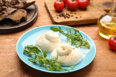 Delicious burrata cheese with arugula on wooden table