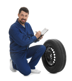 Photo of Professional auto mechanic with wheel and clipboard on white background