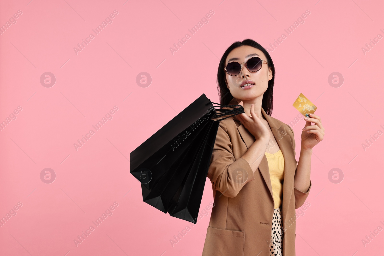 Photo of Beautiful woman with shopping bags and credit card on pink background. Space for text