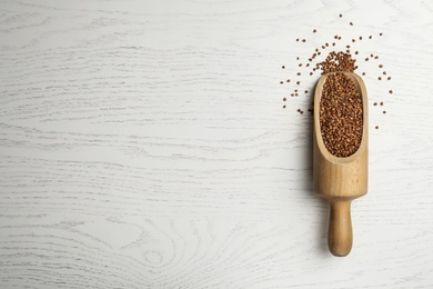 Photo of Buckwheat grains on white wooden table, top view. Space for text