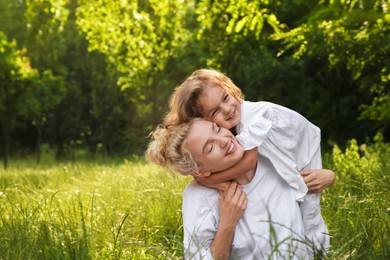 Beautiful mother with her cute daughter spending time together outdoors. Space for text