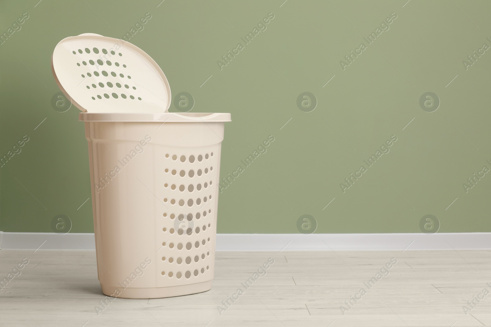 Photo of Empty plastic laundry basket near light green wall. Space for text