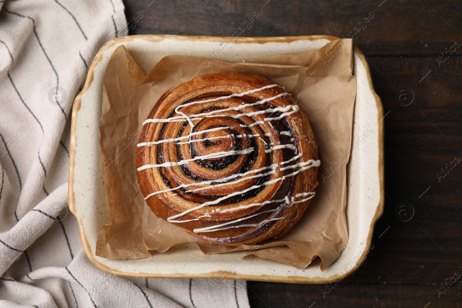 Photo of Delicious roll with topping and poppy seeds on wooden table, top view. Sweet bun