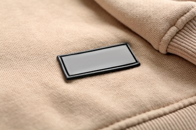 Photo of Blank clothing label on beige sweatshirt, closeup