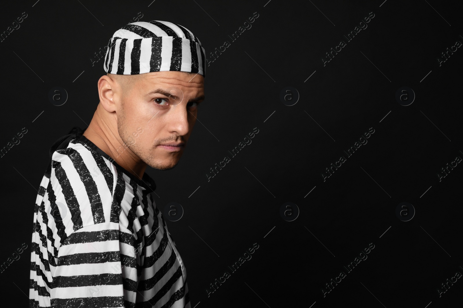 Photo of Prisoner in striped uniform on black background, space for text