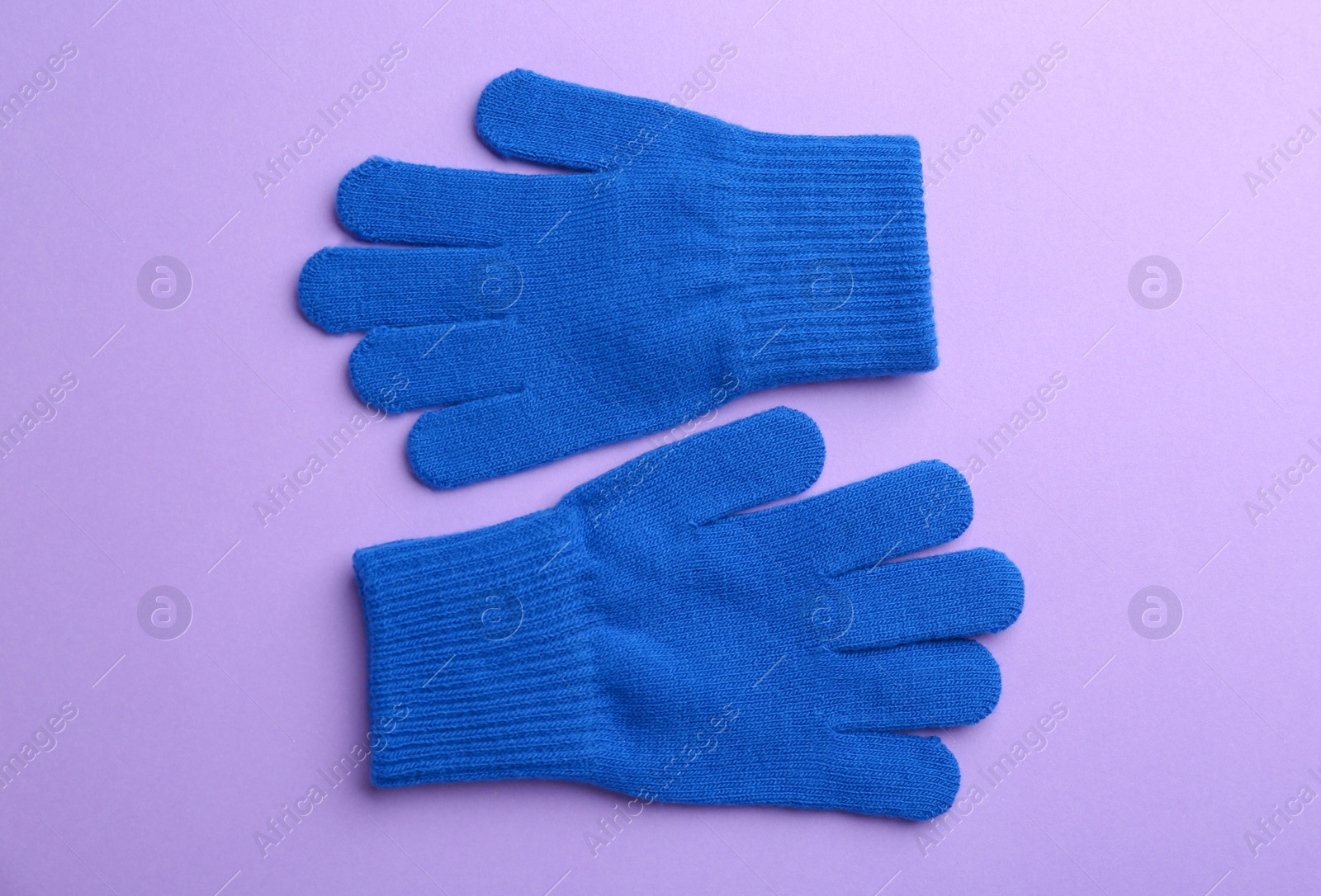 Photo of Pair of stylish woolen gloves on violet background, flat lay