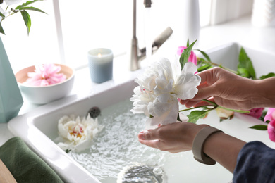 Photo of Woman with beautiful peony near kitchen sink, closeup