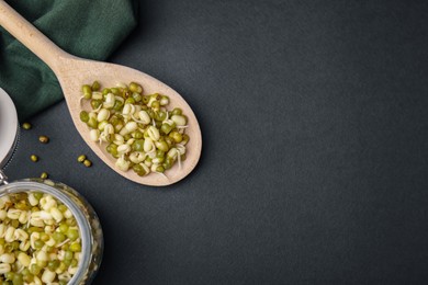 Photo of Wooden spoon with sprouted green mung beans on black background, flat lay. Space for text
