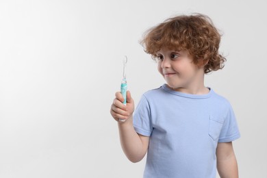 Photo of Cute little boy holding electric toothbrush on white background, space for text