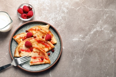 Thin pancakes served with syrup and berries on plate, top view