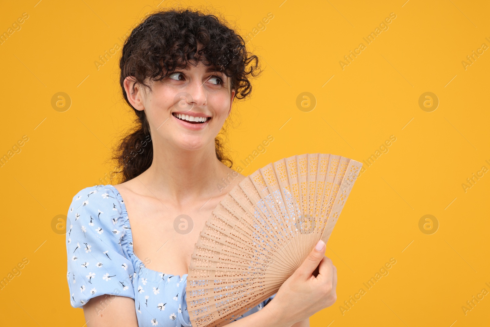 Photo of Happy woman holding hand fan on orange background. Space for text