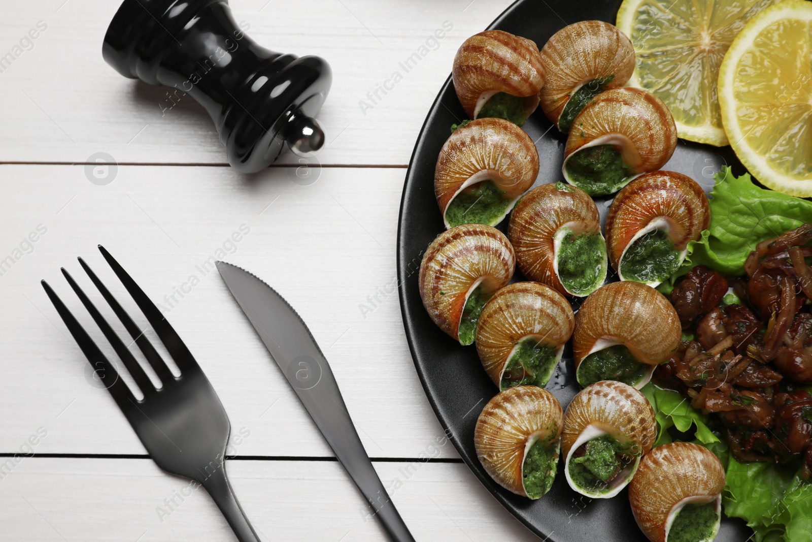 Photo of Delicious cooked snails served on white wooden table, flat lay