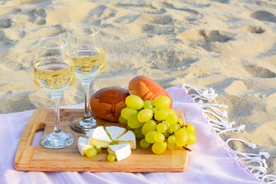 Glasses with white wine and snacks on beach sand outdoors. Space for text