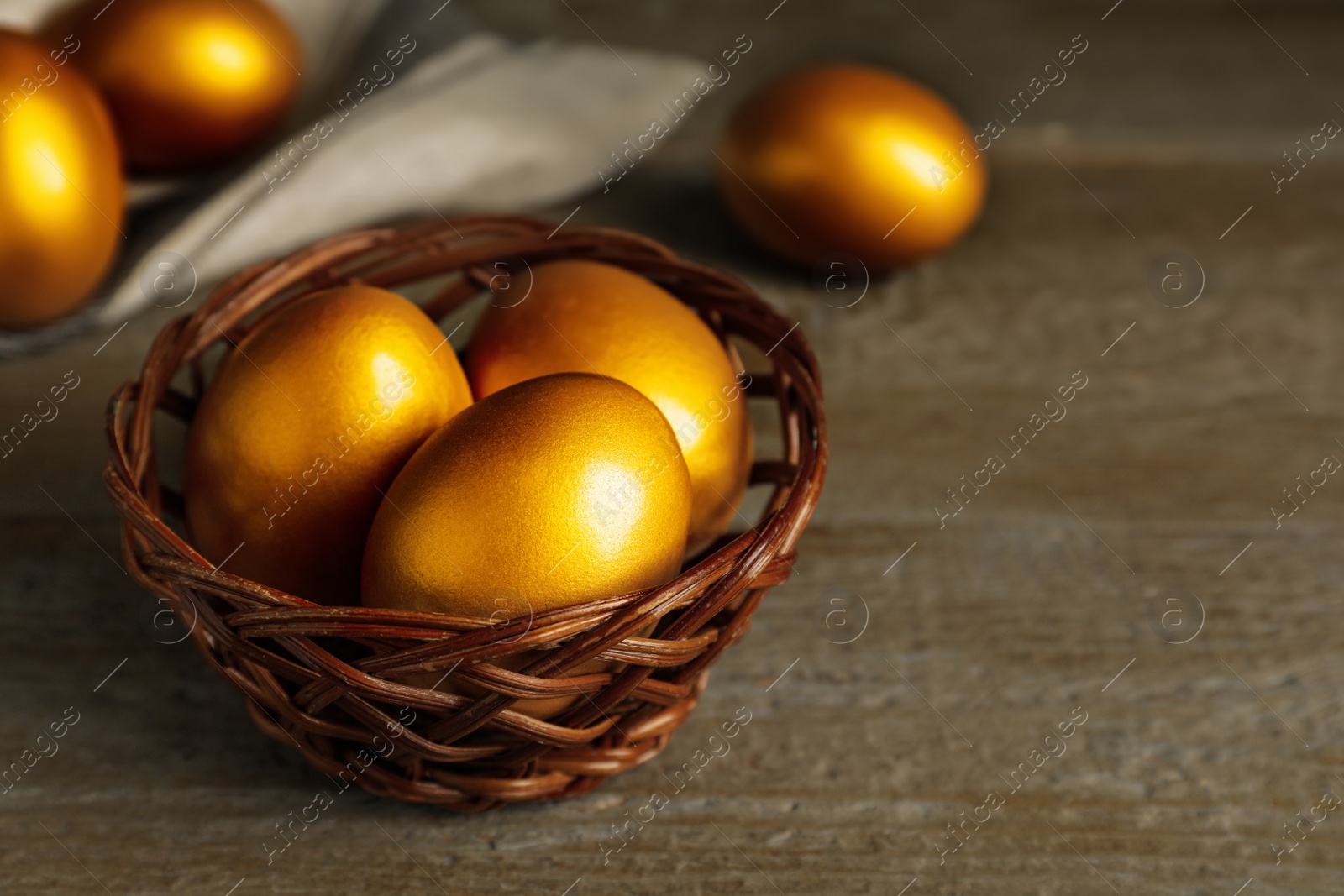 Photo of Golden eggs on wooden table, closeup. Space for text