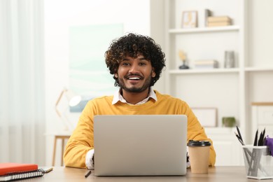 Handsome smiling man using laptop in room