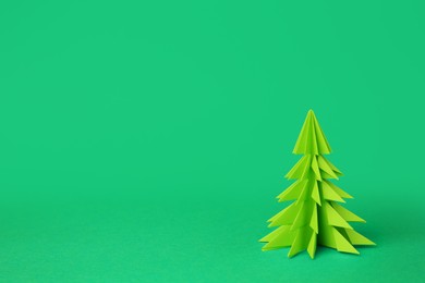 Origami art. Handmade paper Christmas tree on green background, space for text