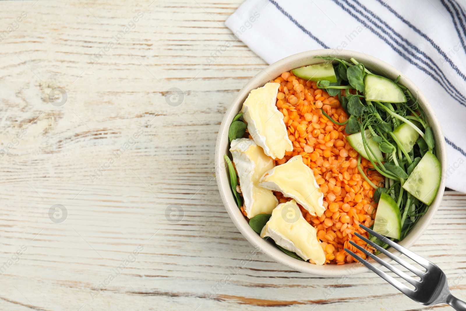 Photo of Delicious lentil bowl with soft cheese and cucumber on white wooden table, flat lay. Space for text