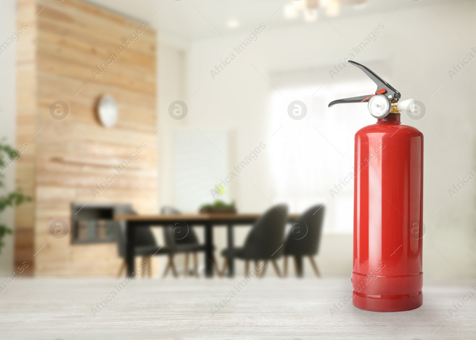 Image of Fire extinguisher on white wooden table in room. Space for text