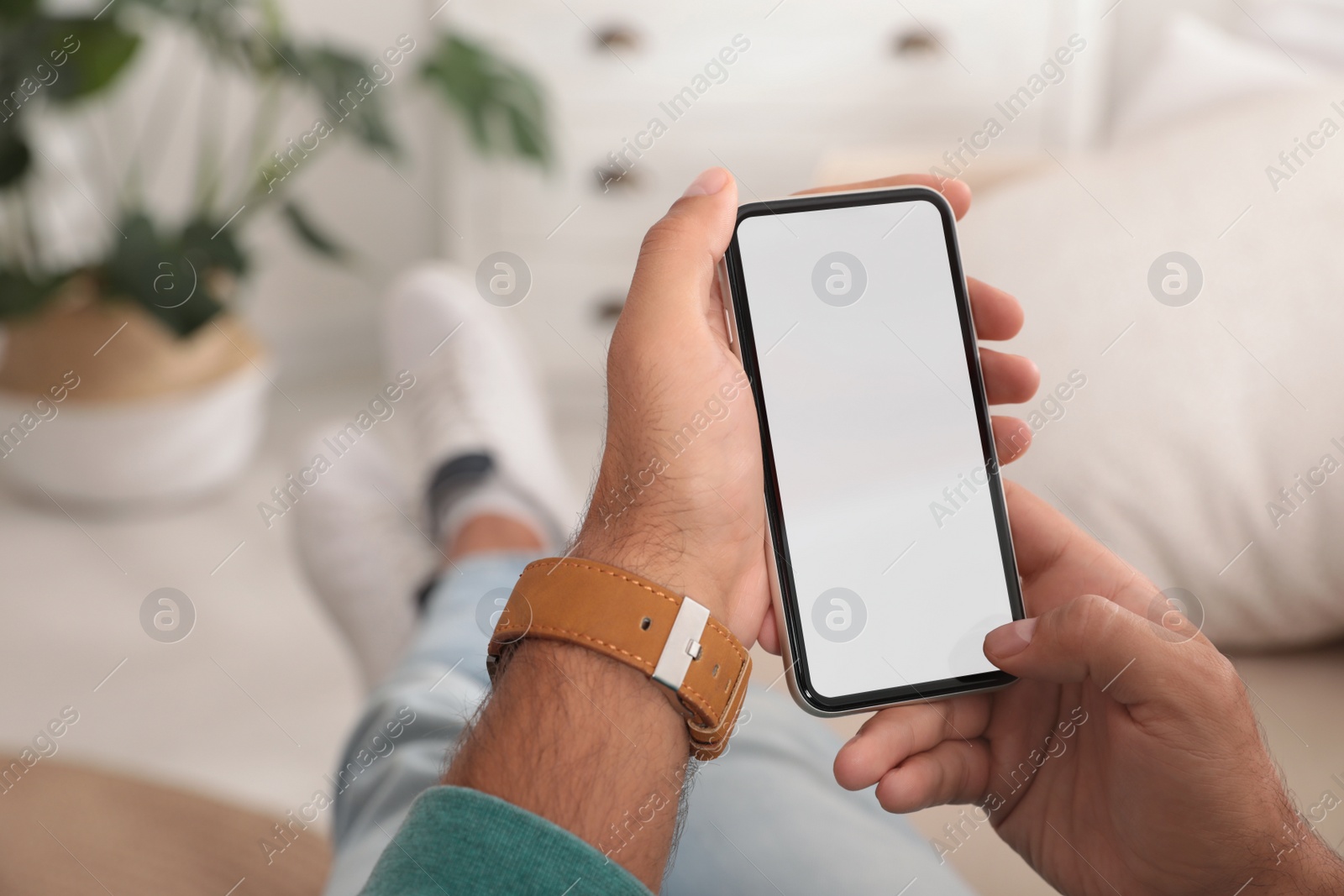 Photo of Man using mobile phone with empty screen indoors, closeup