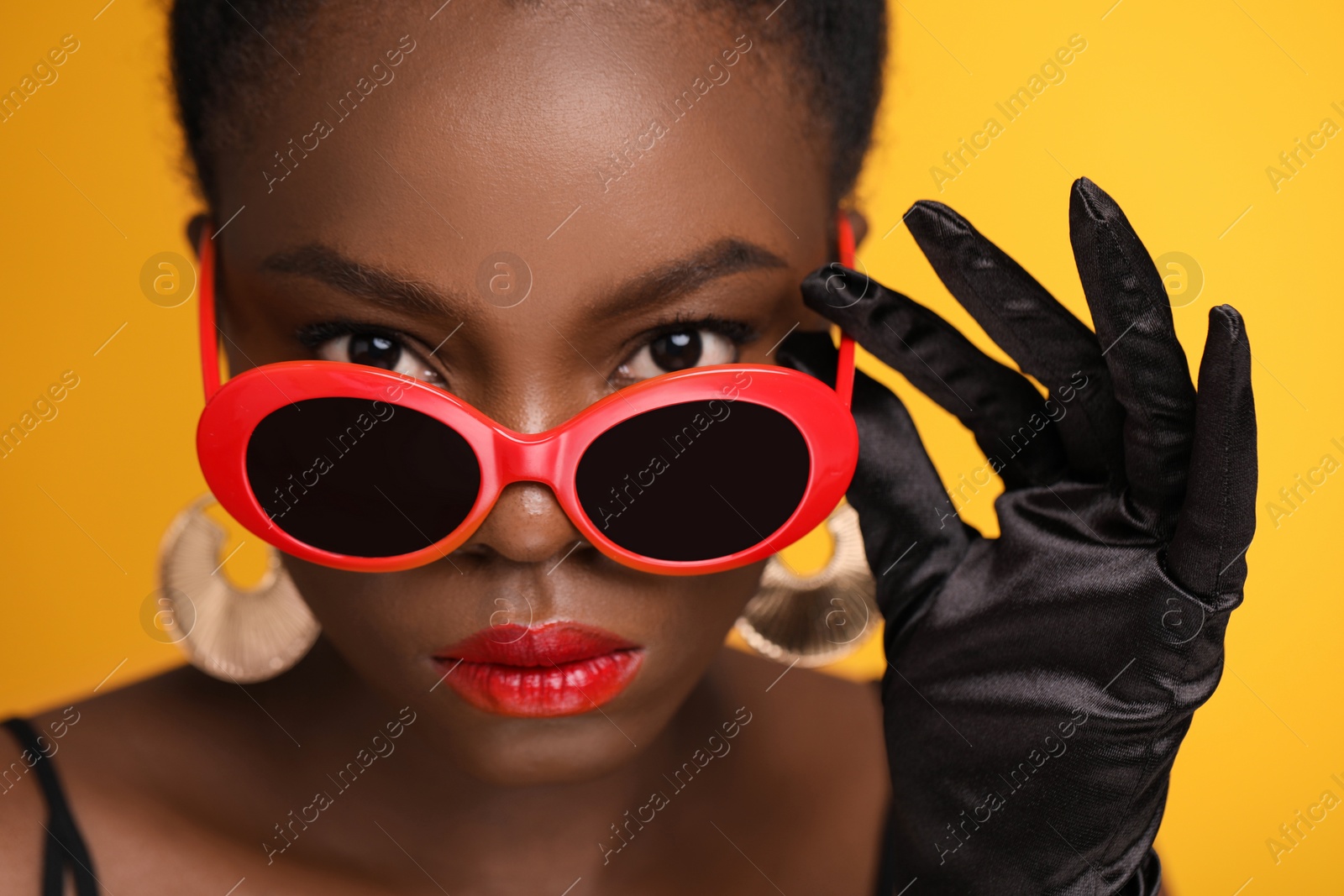 Photo of Fashionable portrait of beautiful woman with stylish sunglasses on yellow background, closeup