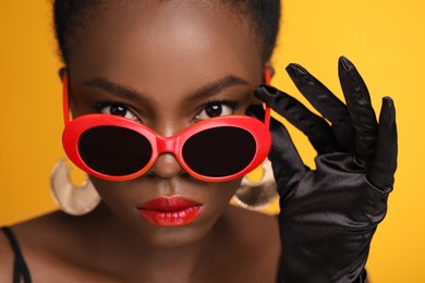 Photo of Fashionable portrait of beautiful woman with stylish sunglasses on yellow background, closeup