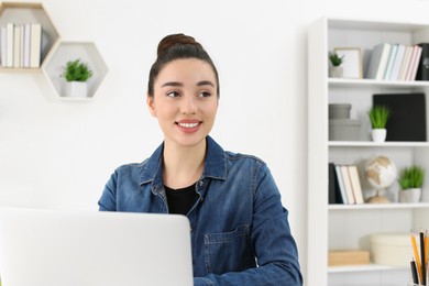 Photo of Home workplace. Happy woman working on laptop in room