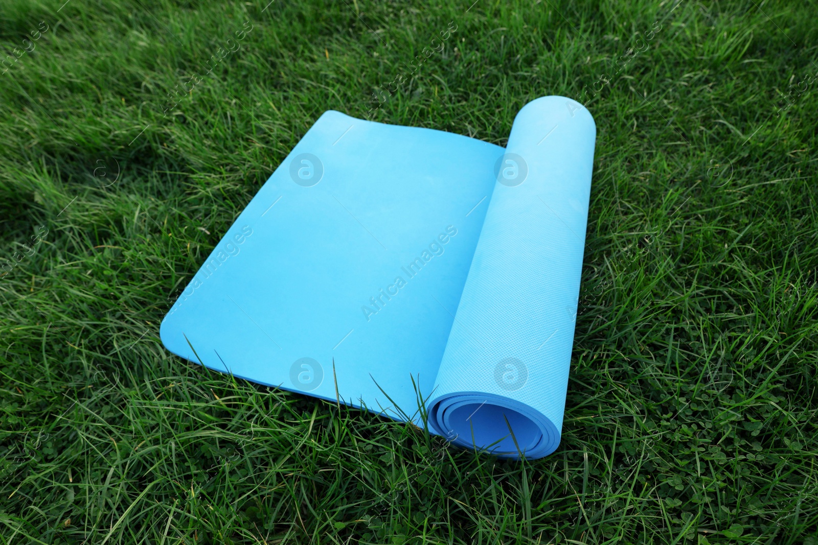 Photo of Blue karemat or fitness mat on fresh green grass outdoors