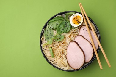 Photo of Delicious ramen with meat on light green background, top view and space for text. Noodle soup