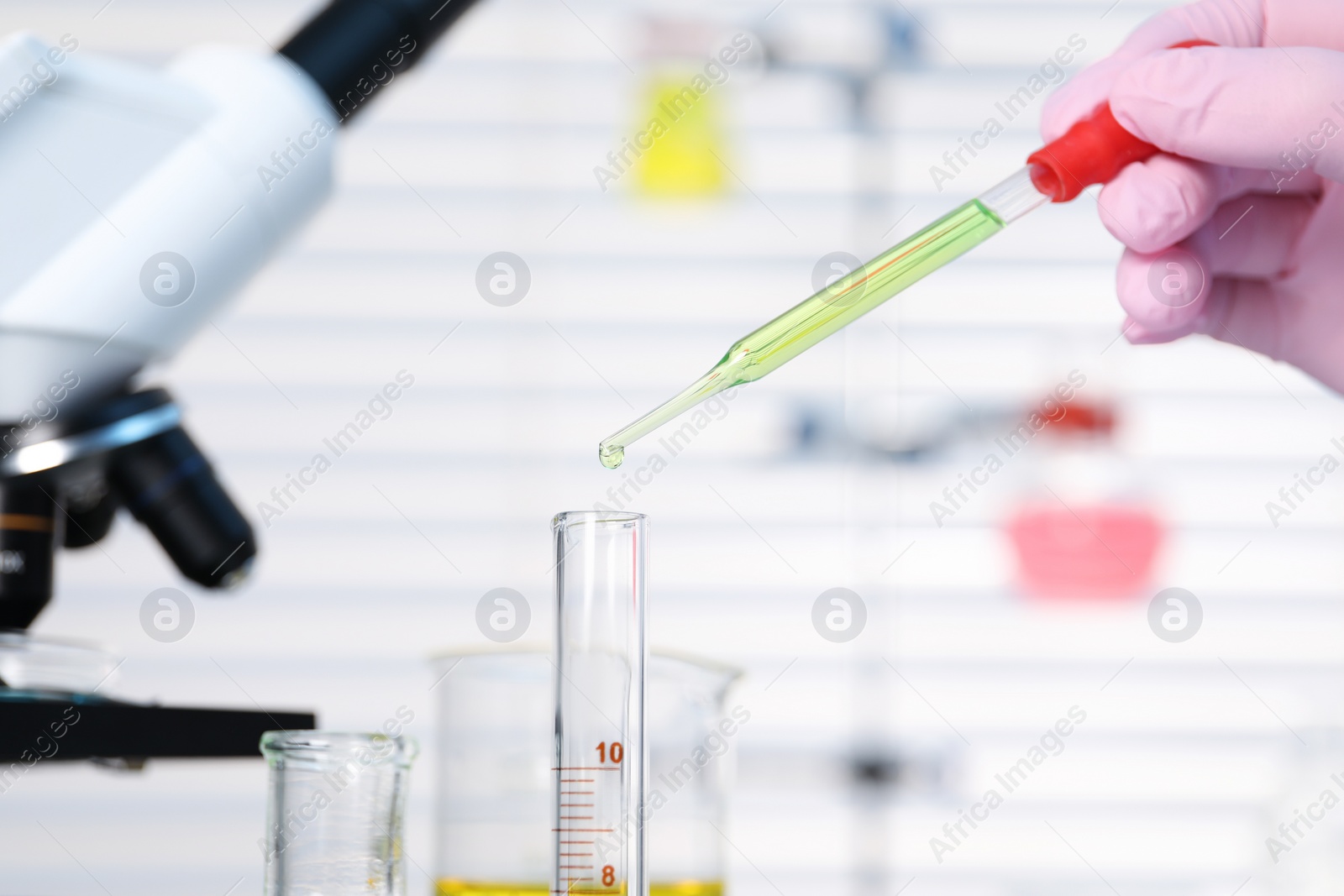 Photo of Laboratory analysis. Woman dripping liquid into test tube on table indoors, closeup